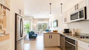 Eine moderne Küche mit Kühlschrank, Mikrowelle, Backofen und einem Essbereich mit Tisch und Stühlen.