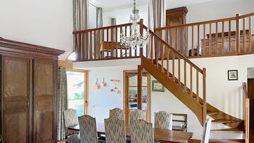 A dining area with a wooden staircase, chandelier, and patterned chairs.
