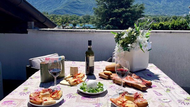 A table set with food and wine, overlooking a mountain range.