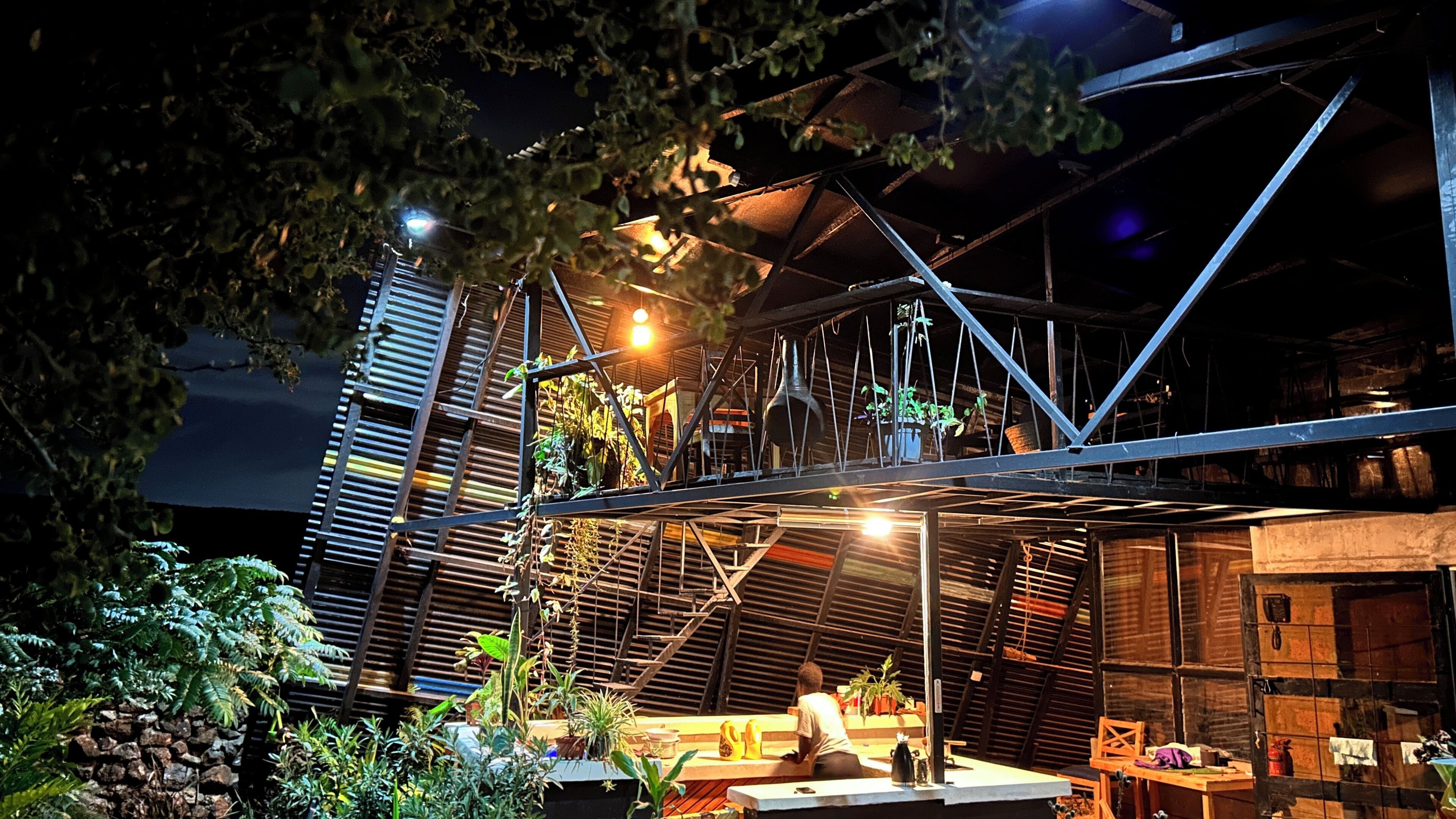 Un jardin sur le toit, avec des plantes en pot, un banc en bois et une personne assise.