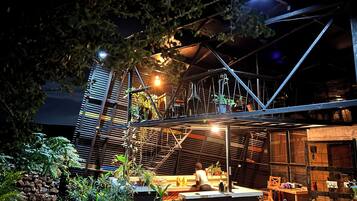 Un jardin sur le toit, avec des plantes en pot, un banc en bois et une personne assise.