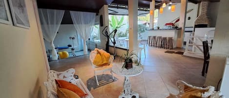 A covered outdoor seating area with white furniture, a small table, and a ceiling fan.