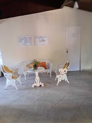 A room with a white sofa, two white chairs, a small round table with a plant, and two framed pictures on the wall. - Family home in a gated community. FAMILY ENVIRONMENT. (Angra dos Reis)