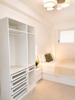 Quarto com cama, mesa de cabeceira, armário e janela com persianas.