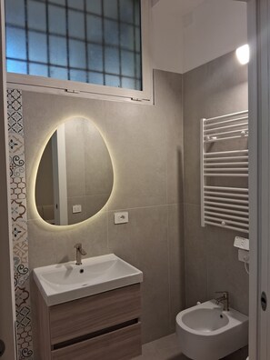 Um banheiro moderno com toucador, pia, espelho e vaso sanitário.