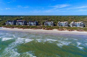Ein Hotel direkt am Strand mit mehreren Gebäuden, einem Sandstrand und Wellen.