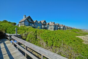 Ein Hotel an der Küste mit einer Holzterrasse und mehreren Balkonen mit Blick auf den Strand.