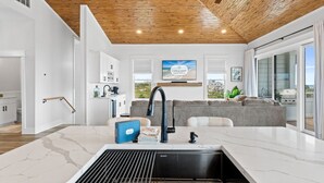 Een moderne keuken met een marmeren aanrechtblad, een zwarte kraan en uitzicht op de stad.
