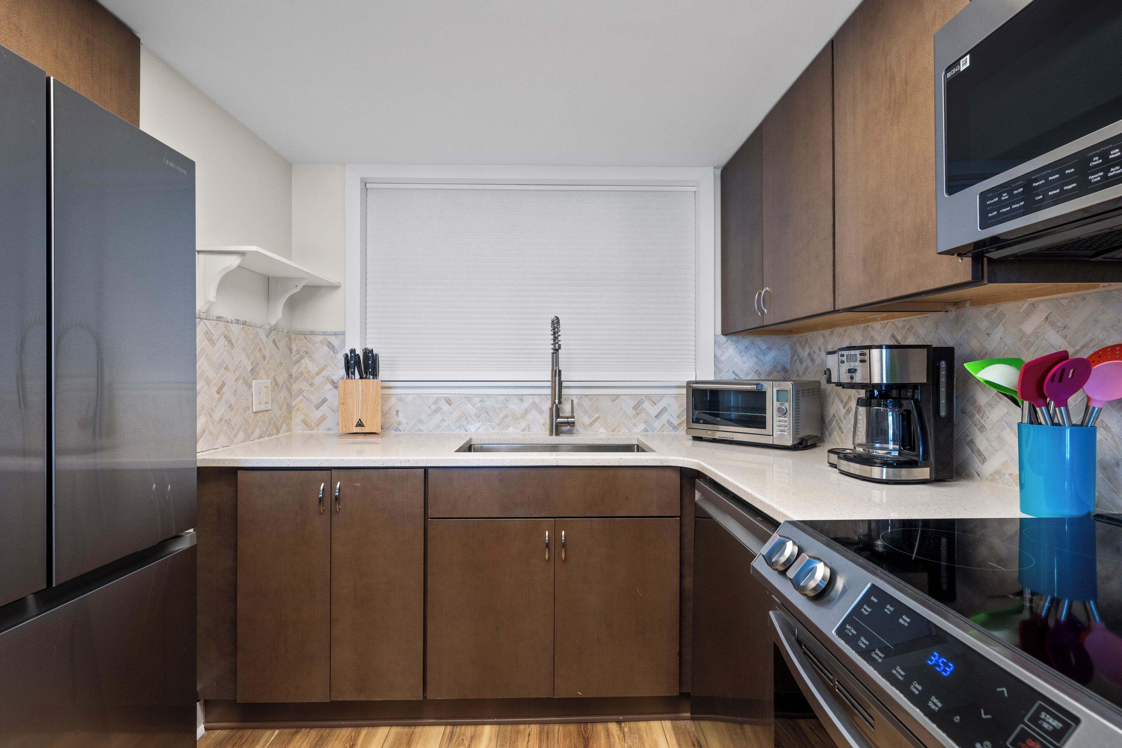 A modern kitchen with a stainless steel refrigerator, microwave, coffee maker, and oven.