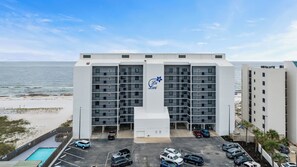 Un hôtel à plusieurs étages doté d’une entrée principale, d’un parking et offrant une vue sur la plage et l’océan.
