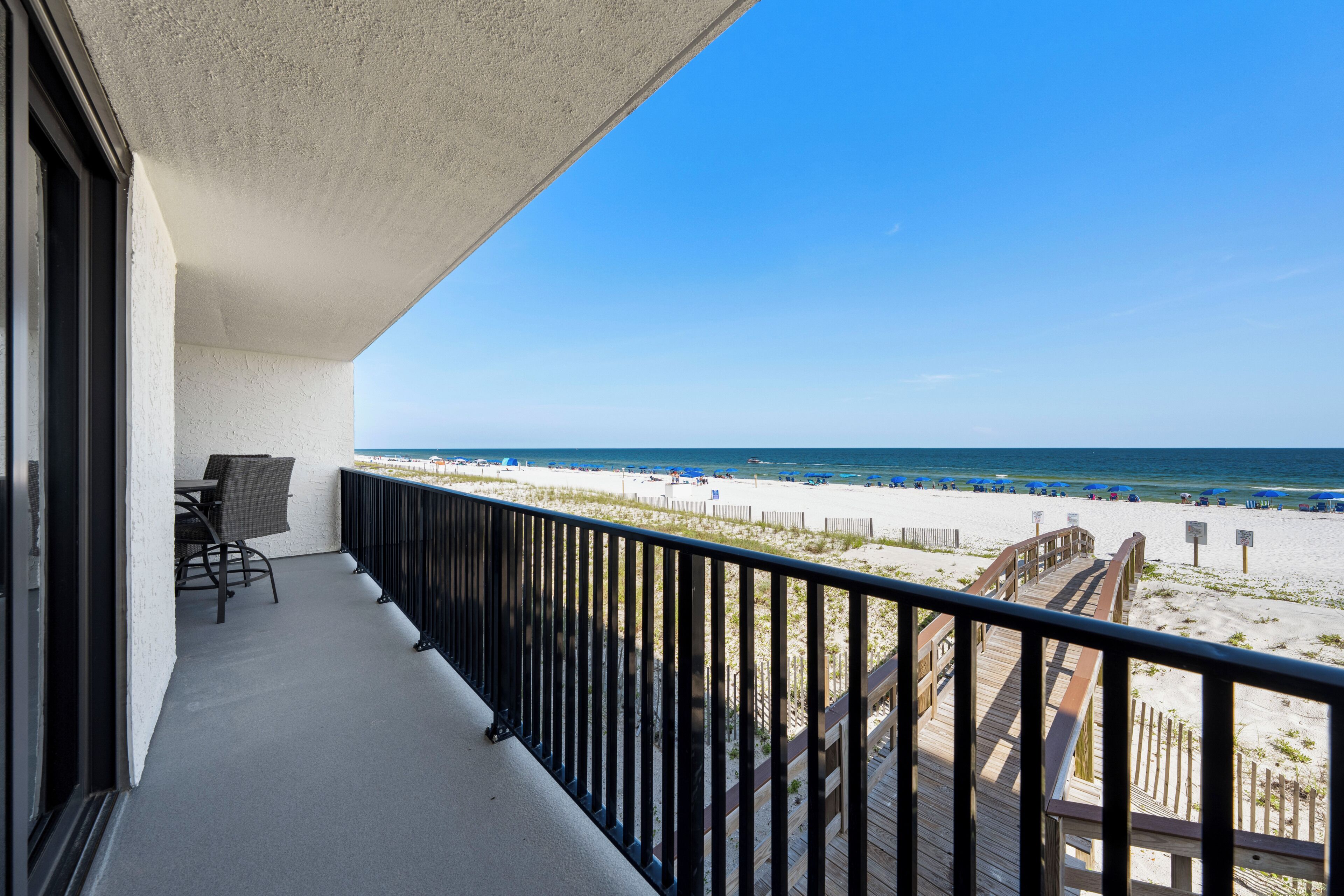 Un balcon avec vue sur la plage, une terrasse en bois et une chaise.