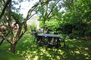 Een terras met een tafel en stoelen, omgeven door weelderige beplanting en bomen.