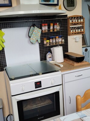 A kitchen with a white stove, oven, and a wall-mounted spice rack. - Apartment 'Saint malo plage 500m (2e étage)' (Saint-Malo)