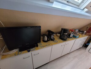 A kitchenette with a television, coffee maker, and cabinets. - Apartment 'Saint malo plage 500m (2e étage)' (Saint-Malo)