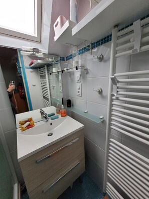 Een moderne badkamer met een witte wastafel, spiegel en handdoekhouder.