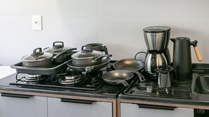 Une cuisine équipée d’une cuisinière, de casseroles, de poêles, d’une machine à café et d’une bouilloire.