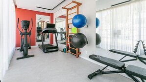 Une salle de sport équipée de matériel d’exercice, d’un tapis de course et d’un banc.