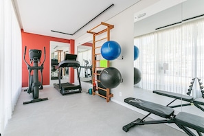 Ein Fitnessraum mit Trainingsgeräten, Laufband und Bank.