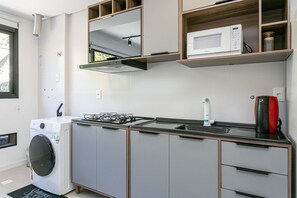Una cocina moderna con lavadora integrada, microondas y estufa a gas.
