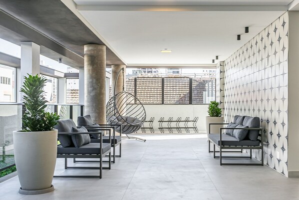 Un área de descanso moderna con asientos, una planta grande en maceta y un adornado panel decorativo.
