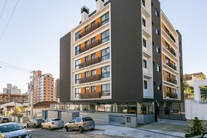 Un edificio residencial de varios pisos con balcones, una entrada con reja y un letrero visible con el número de la dirección.