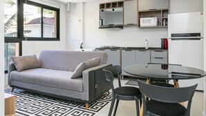 Un espace de vie compact comprenant un canapé, des fauteuils, une table à manger, un four à micro-ondes et un réfrigérateur.