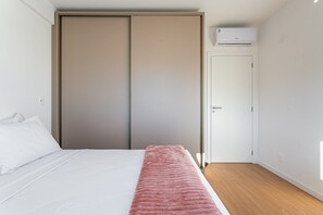 A bedroom with a bed, a pink blanket, a wardrobe, and an air conditioning unit. - Shopping | gastronomy | Everything on foot #CA102 (Florianópolis)