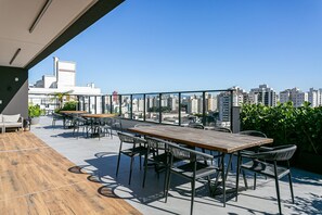 A rooftop terrace with a wooden table and chairs, a view of the city skyline, and a potted plant. - Shopping | gastronomy | Everything on foot #CA102 (Florianópolis)