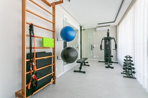 Ein Fitnessraum mit Trainingsgeräten, einer Klimmzugstange und einem an der Wand befestigten Gymnastikball.