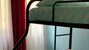 Un lit superposé avec un matelas et des oreillers, une fenêtre avec des rideaux et une structure en métal.