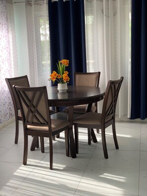 A dining area with a round table, four chairs, and a vase with flowers. - Tremendous 3-bedroom house with AC in Anse La Raye (Anse La Raye)