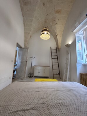 Ein Schlafzimmer mit hoher, gewölbter Decke, einem Bett, einem Schminktisch und einem Fenster.