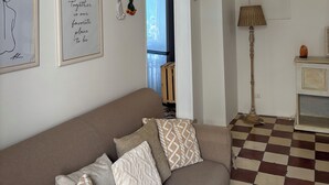 Un salón con sofá, piso a cuadros, lámpara y un arco de piedra.