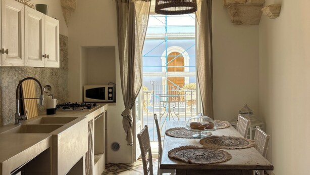 Una cocina con comedor, paredes de piedra, una lámpara colgante y vistas al mar.