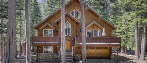 A two-story wooden cabin with a stone foundation, a front entrance, and a garage.