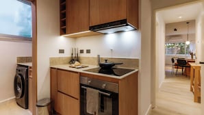 A modern kitchen with wooden cabinets, a built-in oven, a stovetop, and a washing machine. - Hestia en Arenales 2900 (Buenos Aires)