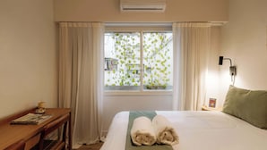 A hotel room with a bed, a desk, a window with curtains, and an air conditioner. - Hestia en Arenales 2900 (Buenos Aires)
