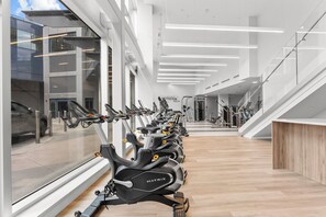 Ein modernes Fitnessstudio mit Ergometer, einer Treppe und großen Fenstern.