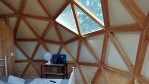 A cozy, triangular wooden room with a bed, a small table, and a TV.
