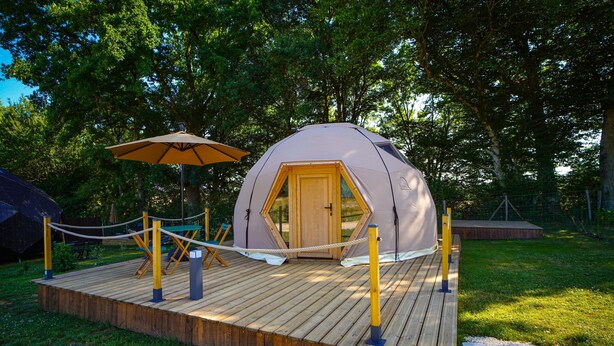 A dome-shaped tent with a wooden door, a rope barrier, and a wooden deck.