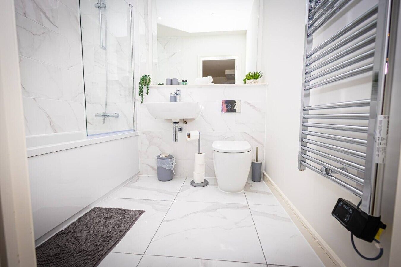 Ein modernes Badezimmer mit Dusche, Toilette, Waschbecken und Handtuchhalter.