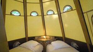 Une chambre avec deux lits, une petite table et trois fenêtres.