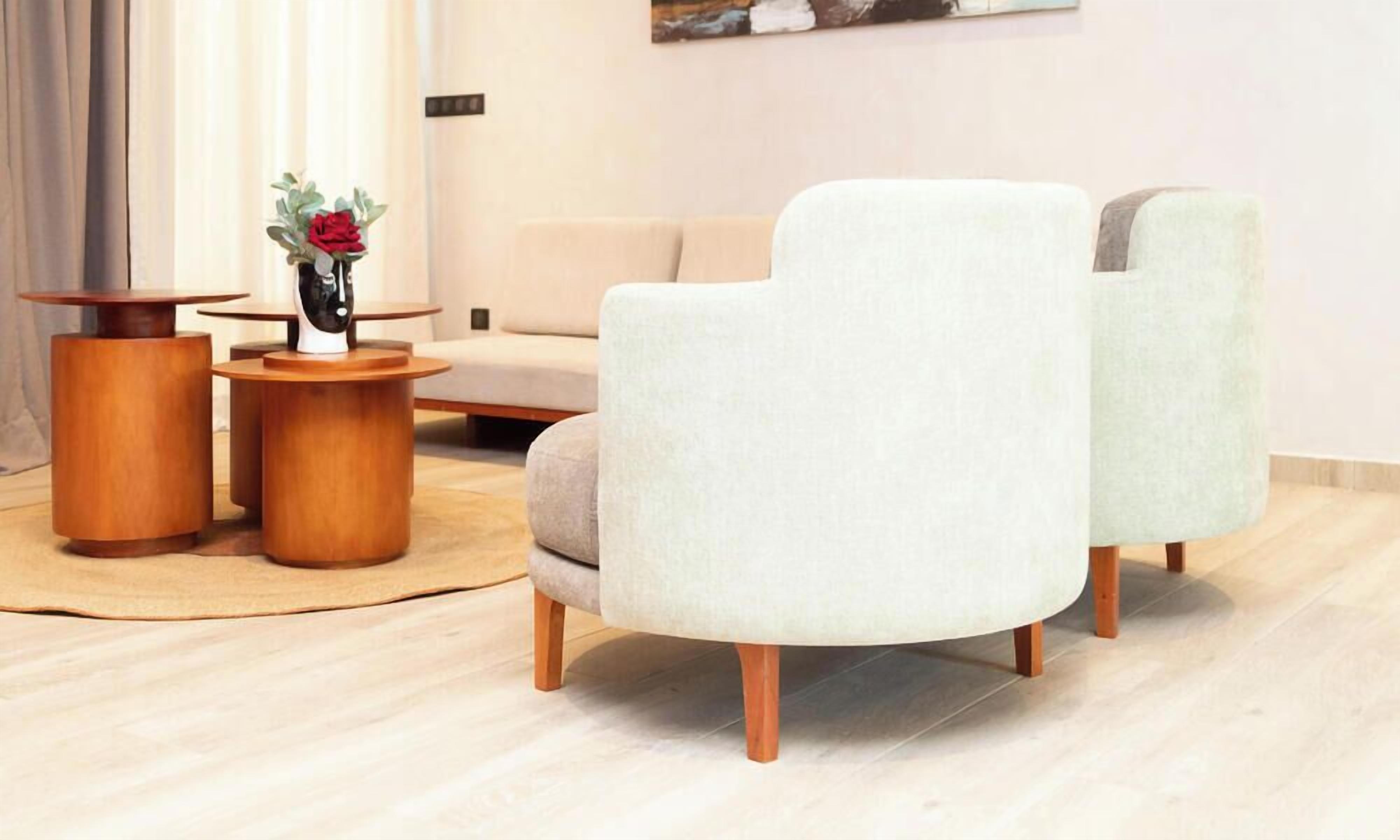 A modern living room with a sofa, two side tables, and a vase with a flower.