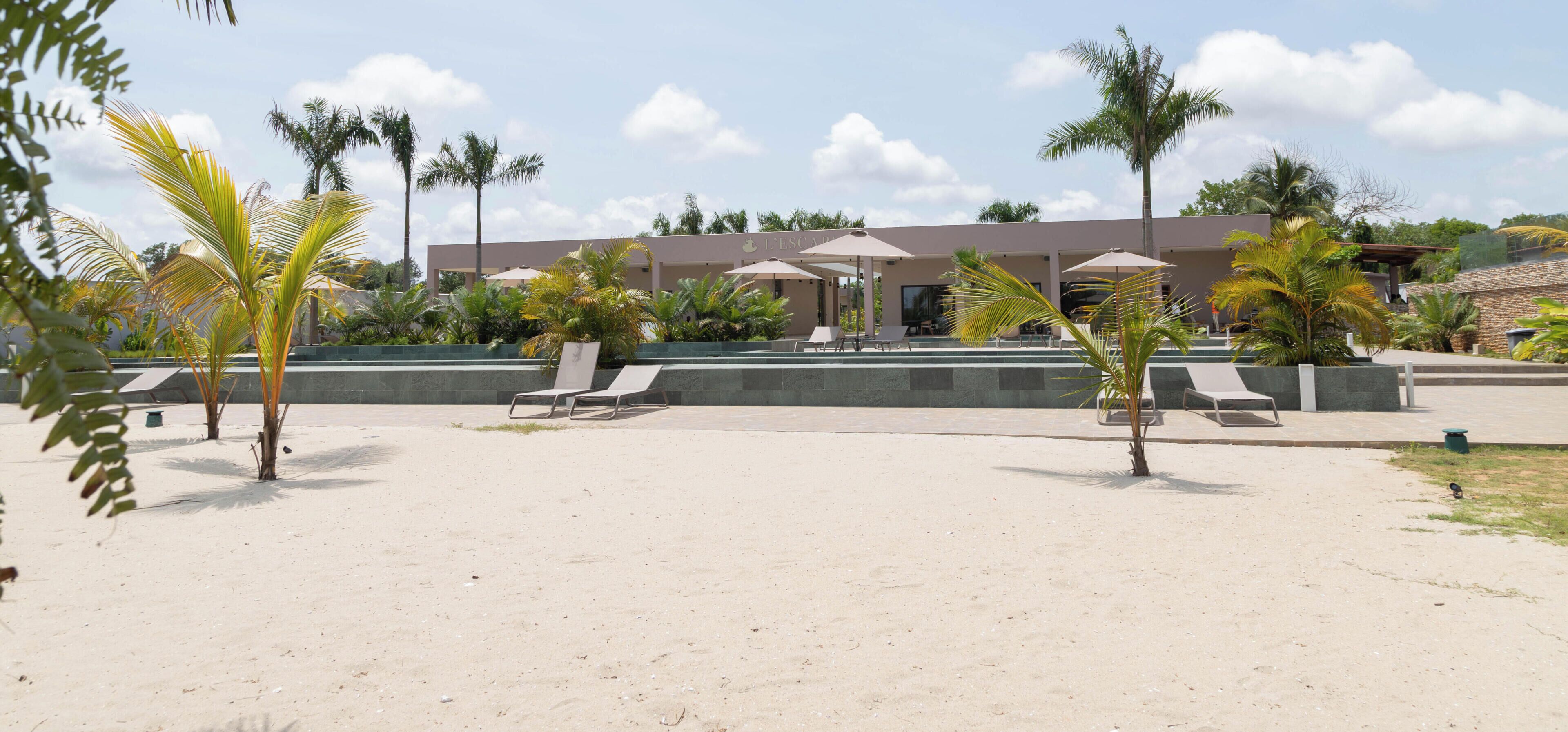 Ein Resort mit Poolbereich, Liegestühlen und Palmen.