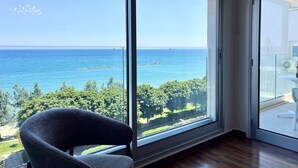 A room with a large window offering a view of the sea and greenery. - 159 LIM - Stay Sea Pearl Apartment (Limassol)