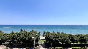 A coastal view with a clear sky, a pathway leading to the beach, and a few ships in the distance. - 159 LIM - Stay Sea Pearl Apartment (Limassol)