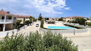 Zona residencial con piscina, casas con techos de tejas rojas y cielo despejado.