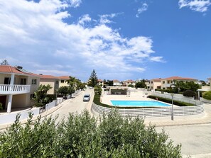 Zona residencial con piscina, casas con techos de tejas rojas y cielo despejado.