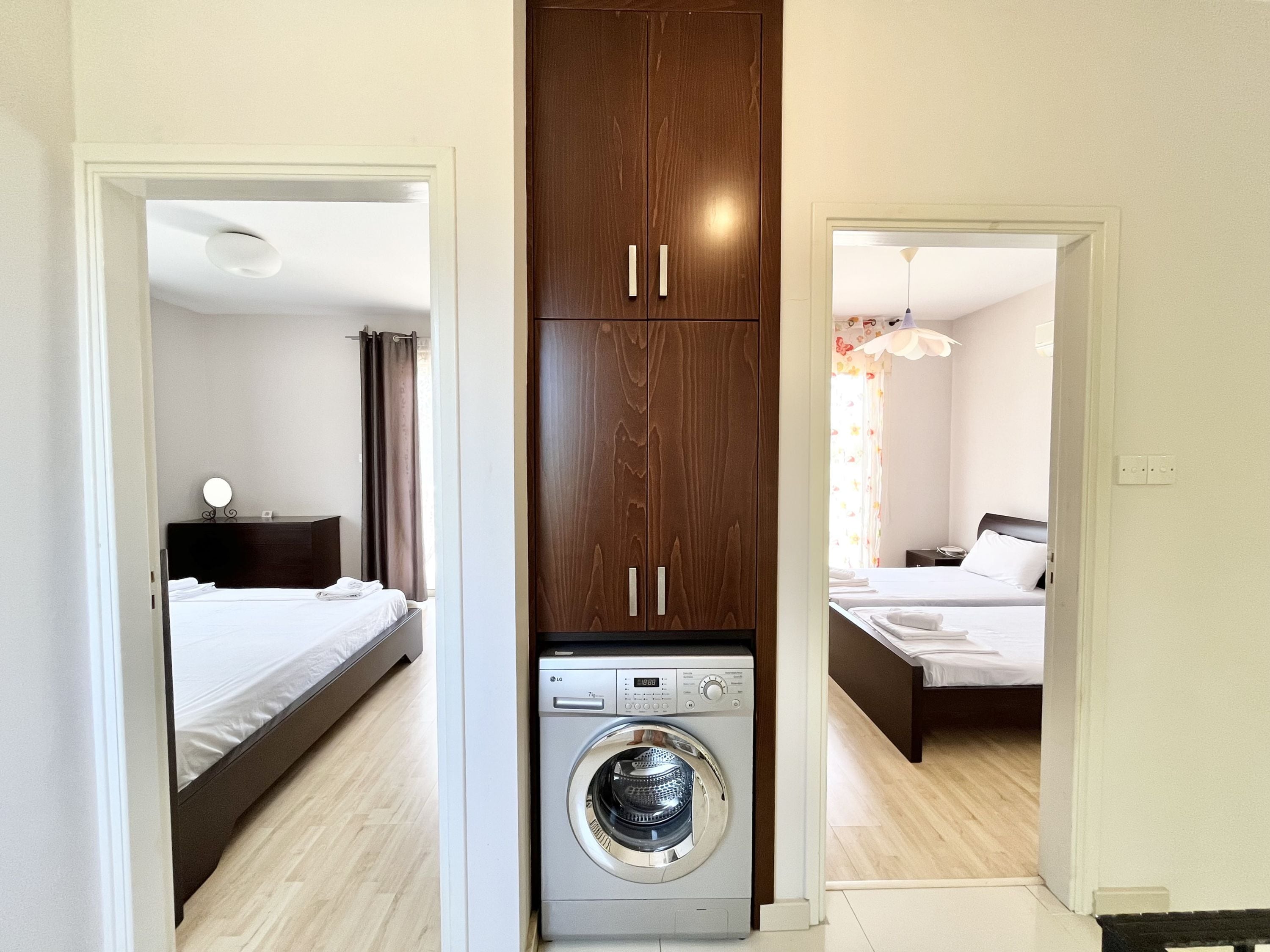Een kleine hotelkamer met een bed, een wasmachine en een kledingkast.