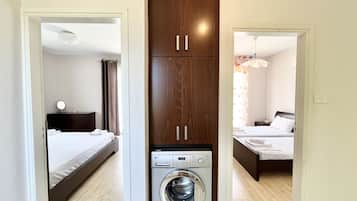 A compact hotel room with a bed, a washing machine, and a wardrobe.